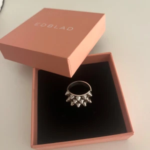 Silverfärgad ring med nitar från Edblad - Snygg ring från Edblad i silverfärg med nitar. I storlek xi (19,5 mm). Säljer på grund av att den inte kommer till användning längre 