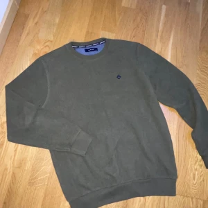 Olivgrön tröja från Gant - OBS: Pris kan diskuteras samt vid snabb affär kan sänkas pris.   Säljer en stilren olivgrön tröja från Gant. Tröjan har en rund halsringning och ett diskret emblem på bröstet. Perfekt för en avslappnad look. Passar bra om du vill ha en modern och grich still väldig fin 