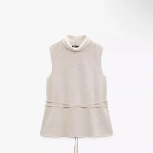 Beige ärmlös topp från Zara - Snygg beige ärmlös topp från Zara med hög krage och knytband i midjan. Kontakta för fler bilder