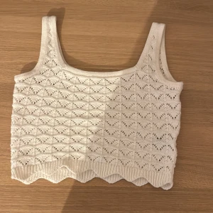 Vit stickad linnetopp från H&M - Säljer en söt vit stickad linnetopp från H&M. Toppen har ett fint hålmönster och ribbad nederkant. Perfekt för varma dagar eller som ett lager under en jacka.