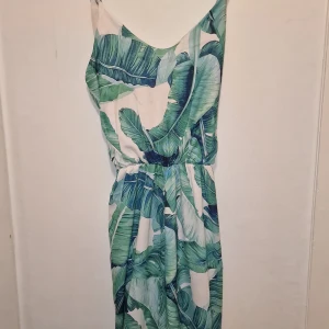 Grönmönstrad jumpsuit - Säljer en somrig jumpsuit med knytband i midjan för en smickrande passform. Perfekt för varma dagar och ger en tropisk känsla.