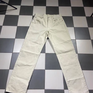 Beige jeansbyxor från Replay - Snygga beige jeansbyxor från Replay med klassisk femficksdesign och knappgylf. Perfekta för en stilren look. Byxorna har en rak passform och är tillverkade i ett slitstarkt material.