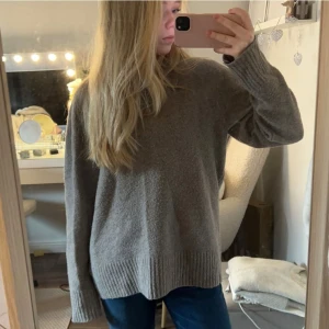 Grå stickad tröja - Mysig grå stickad tröja med långa ärmar och ribbade muddar. Perfekt för kyligare dagar och ger en avslappnad look. Passar bra till jeans eller leggings.