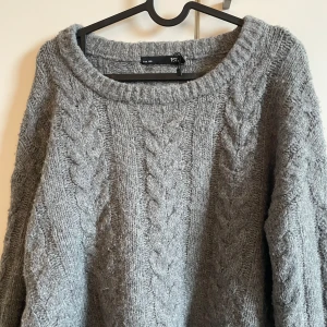 Grå stickad tröja från lager 157 - Säljer en mysig grå stickad tröja från lager med kabelstickat mönster. Tröjan har långa ärmar och en rund halsringning. Perfekt för kyliga dagar!