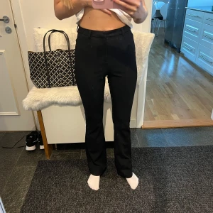 Svarta byxor - Säljer ett par svarta kostybyxor i bra skick. De är högmidjade och har en bootcut passform. Perfekta för både vardag och fest!
