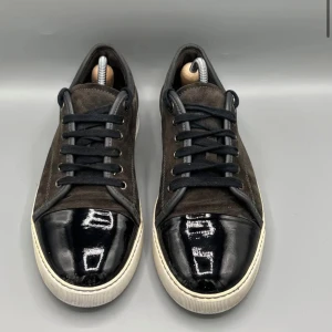 Svarta sneakers från Lanvin - Säljer ett par snygga svarta sneakers från Lanvin. De har en cool kombination av mocka och skinn med en glansig tå. Skorna har en vit sula och klassisk snörning. Skick 6 -10Perfekta för både vardag och fest! Storlek UK 8 och passar storlek 43/44 bäst
