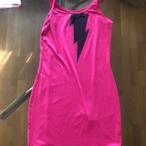 En lång rosa träningströja - En lång rosa träning med en svart blixt i bröstområdet