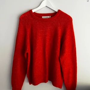 Stickad tröja från Carin Wester  - Fint skick. Nästan helt oanvänd. Är i rödorange färg.