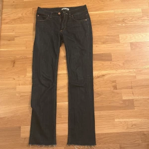 Low-Waist Bootcut Svarta Acne Jeans - Säljer ett par snygga lågmidjade mörkblåa jeans från Acne Jeans. De är i mycket bra skick och passar Xs-S. De Perfekta om man är lite mer petit då de inte är så långa, långstans mellan 150-160 cm är perfekt längd. 