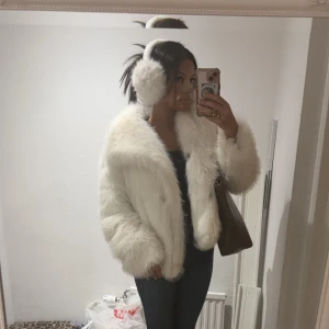 Vit pälsjacka - Säljer en fluffig och stilren vit pälsjacka som är perfekt för kyliga dagar. Jackan har en klassisk design med långa ärmar och en mjuk känsla. Passar utmärkt för att hålla värmen med stil.