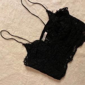 Svart spetslinne från Pieces - Snyggt svart spetslinne från Pieces med tunna axelband och vacker spetsdetalj. Perfekt för en stilren och elegant look. Passar bra till både jeans och kjol.