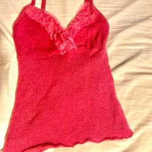 Rosa stickad linnetopp - Säljer en söt rosa stickad linnetopp med spetsdetaljer vid halsringningen. Perfekt för varma dagar eller som ett lager under en kofta. Toppen har smala axelband och en figurnära passform.