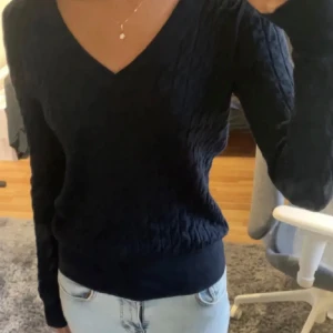 marinblå ribbad tröja med v-ringning - Snygg svart tröja med v-ringning och ribbade detaljer. Perfekt för en stilren look. Långärmad och passar bra till jeans eller kjol.