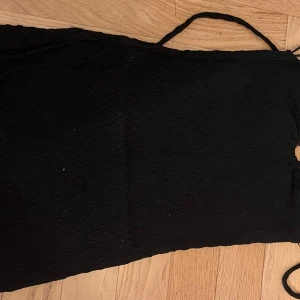 Beige och svart strandklänning - Snygg beige stickad klänning med ett diskret mönster och smala axelband. Perfekt för en stilren look. 50 kr st. 80 kr för båda