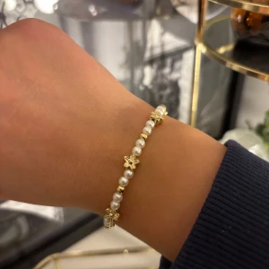 Guldarmband med pärlor och blommor - Egengjort armband i vit och guld med blommor. Kan fixa flera, eller andra varianter, både i silver och guld. Har ni eget förslag eller önskemål är det bara att höra av sig🩷🩷