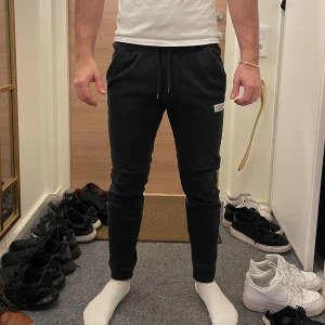 Svarta mjukisbyxor från Björn Borg - Snygga svarta mjukisbyxor från Björn Borg med snörning i midjan och en liten logga på benet. Perfekta för en avslappnad stil. Byxorna har en normal passform och är tillverkade i mjukt material för extra komfort.