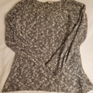 Gråmelerad stickad tröja från Comma - Säljer en snygg gråmelerad stickad tröja från Comma. Tröjan har ett diskret mönster och långa ärmar, perfekt för kyligare dagar. Den är tillverkad i en mjuk och bekväm materialblandning.