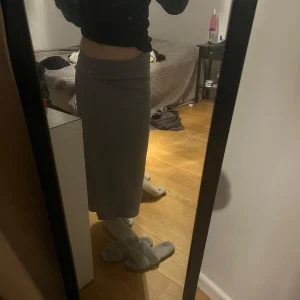 Grå långkjol - Snygg grå långkjol i en stilren design. Perfekt för en elegant och avslappnad look. Kjolen har en enkel passform och är lätt att matcha med olika toppar.
