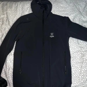 Svart vindjacka Haglöfs - Dragkedja på fickor. Köpt i somras och använd 5-8 ggr, mjukare skaljacka med avrinning.