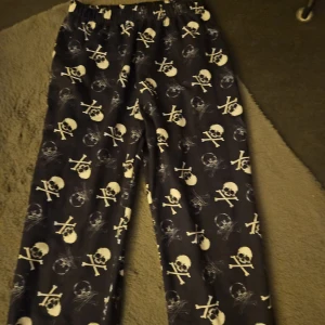Svarta pyjamas/byxor - Svarta pyjamas/ byxor med ett mönster av vita dödskallar och ben. Byxorna har en resår i midjan och i bensluten. Kan användas av både en som har s och m