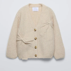 Beige stickad kofta med knappar och rosett - Köp direkt för 450!!!Mysig beige stickad kofta från Zara med stora knappar och en dekorativ rosett på sidan. Perfekt för kyliga dagar med sin mjuka och varma känsla. 💞💞💘💝 Storlek 13-14 sitter som en s🙌🏻Den är lite anvönd men inga tydliga defekter, små noppring❤️