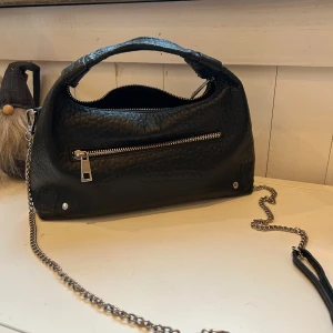 Svart väska - Väska från nunoo med tre fack, två med dragkedja och ett utan, axelbandet är avtagbart