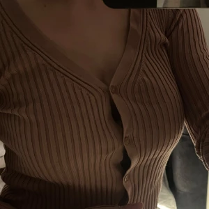 Ribbad rosa kofta  - Säljer en  rosa ribbad kofta från H&M. Den har en v-ringad design med knappar framtill och långa ärmar. Använd max 2-3 gånger 