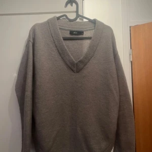 Grå tröja från Ellos - Säljer en stilren grå tröja från Ellos med v-ringning. Tröjan har långa ärmar och är tillverkad i ett mjukt material som passar perfekt för kyligare dagar. Perfekt för en avslappnad och bekväm look.