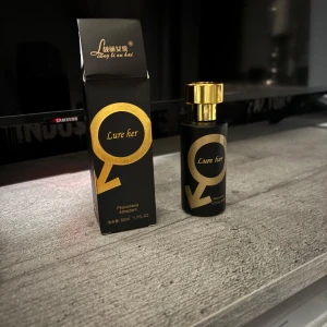Lure Her Pheromone Parfym - (Helt ny oanvänt) Elegant parfymflaska i svart med gyllene detaljer och text. Innehåller 50 ml av en förförisk doft med feromoner, designad för att attrahera. Flaskan har en lyxig gyllene kork och kommer i en matchande svart och guld kartong, produkten är beställd och om det verka få ditt intresse skriv gärna.