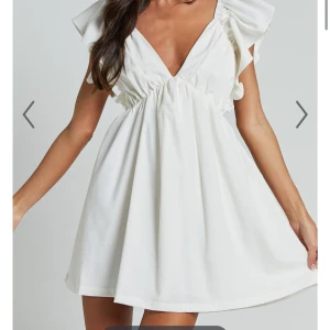 Vit kortklänning med volangdetaljer från showpo - Vit kort klänning med volangdetaljer, köpt ifrån showpo. Perfekt till sommaren eller som en studentklänning!! Helt ny med lappar kvar och helt oanvänd. Säljes pga jag hittat studentklänningen jag ska ha istället💕