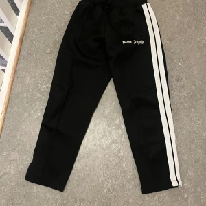 Svarta byxor med vita ränder från Palm Angels - Snygga svarta byxor från Palm Angels med vita ränder längs sidorna. 