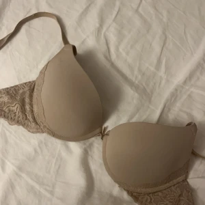 Beige spets-bh från Lindex  - Elegant beige bh med spetsdetaljer på sidorna. Den har justerbara axelband och en slät kupa för en bekväm passform. Perfekt för en stilren look. Lite push-up. Använd fåtal gånger❤️❤️