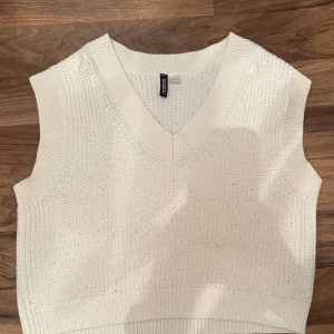 Vit stickad väst från H&M - Snygg vit stickad väst från H&M med v-ringning. Perfekt för lager-på-lager-stil och passar till många olika outfits. Enkel och stilren design.💕