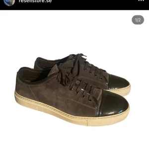 Bruna sneakers med svarta detaljer - Säljer ett par bruna sneakers med svarta detaljer. Skorna har en snygg kombination av mocka och skinn, vilket ger dem en unik look. De har snörning och en vit sula som ger en skön kontrast. Perfekta för både vardag och fest!