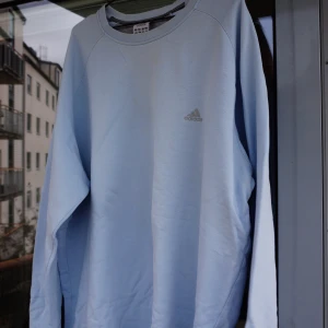 Tröja  - Tröja från Adidas i en ljusblå färg. 2XL, men sitter betydligt större. Finns några fläckar som syns på andra bilden. Därav det lägre priset. Kolla gärna profilen. Säljer gärna flera plagg samtidigt. Frakt tillkommer. 