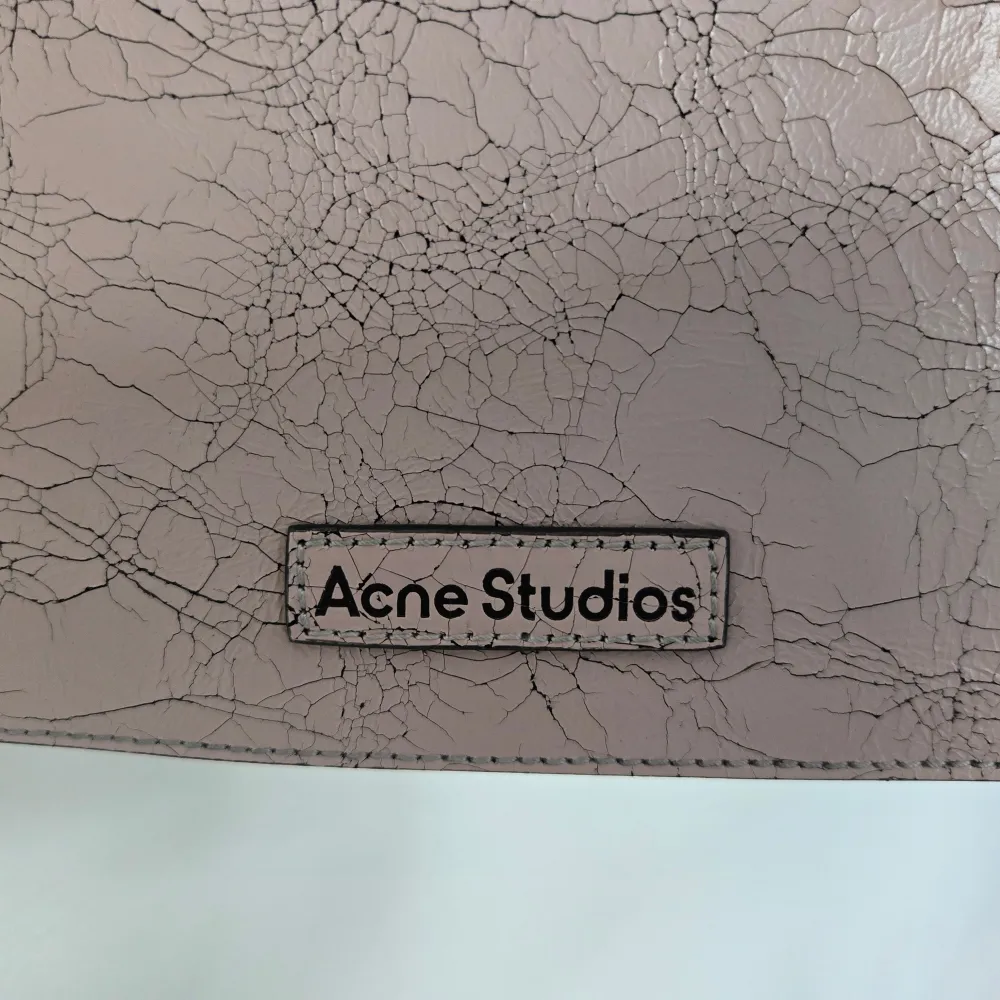 Aldrig använd Acne Studios Platt Micro axelväska i pastel pink. Väskan har en unik krackelerad yta som ger den en cool och annorlunda look. Den är gjord i skinn och har en praktisk dragkedja upptill. Nypris 8300kr.. Väskor.