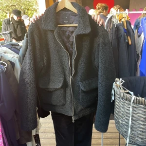 Svart teddyjacka från New Look - Säljer en supermysig svart teddyjacka från New Look i storlek M. Jackan har en dragkedja framtill och stora fickor som är perfekta för att hålla händerna varma. Den är perfekt för höst och vinter, och den quiltade insidan gör den extra varm och skön!
