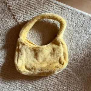 Super gullig handväska - Liten handväska från Monki i populär modell. Ljusgul och fluffig med dragkedja samt rymmer mer än vad man tror. Perfekt färgklick till en outfit!⭐️