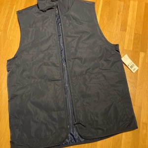 Ny täckväst - Blå väst med lappen kvar