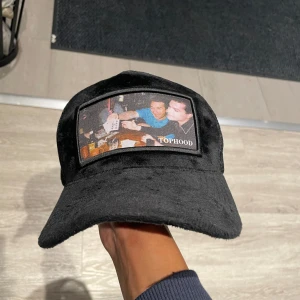 Svart Velvet Keps från Tophood - !LIMITED ! en svart keps från Tophood med en unik patch framtill som visar ett foto. Kepsen har en klassisk design med justerbar rem baktill och meshmaterial för bra ventilation. Perfekt för en avslappnad stil! Den är gjort av Velvet! Top material 💯 