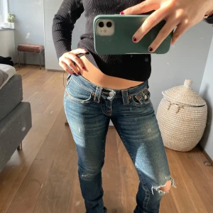 Blå jeans med slitningar - Säljer ett par lågmidjade blå jeans med slitningar sond design. De har även fina detaljer så som på fickorna. Märke: True Religion, Storlek 24/30 men också 25/30. Köpte för 1200kr, är nästan helt oanvända