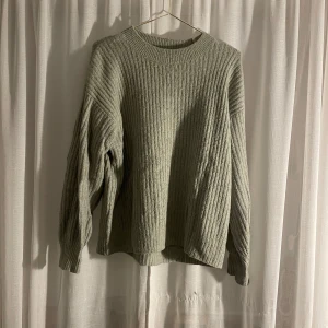 Grå ribbad tröja från H&M - Säljer en supermysig grå ribbad tröja från H&M. Perfekt för kyliga dagar med sin mjuka och bekväma passform. Tröjan har långa ärmar och en klassisk rund halsringning. Använd men inga skador som t.ex hål🌟