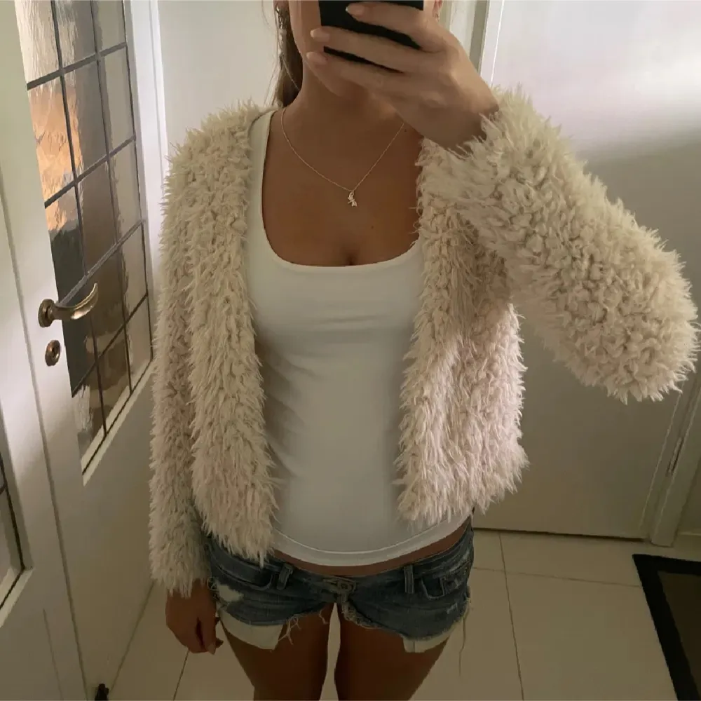 Mysig beige teddyjacka med långärmad design. Perfekt för att hålla sig varm och stilren under kyligare dagar. Jackan har en fluffig textur som ger en trendig look.. Takit.