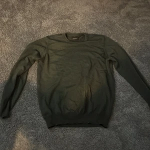 Oscar jacobson tröja  - Säljer en stilren grön tröja från Oscar Jacobson, tillverkad i Italien. Tröjan har långa ärmar och en klassisk rund halsringning. Perfekt för en elegant och avslappnad look.
