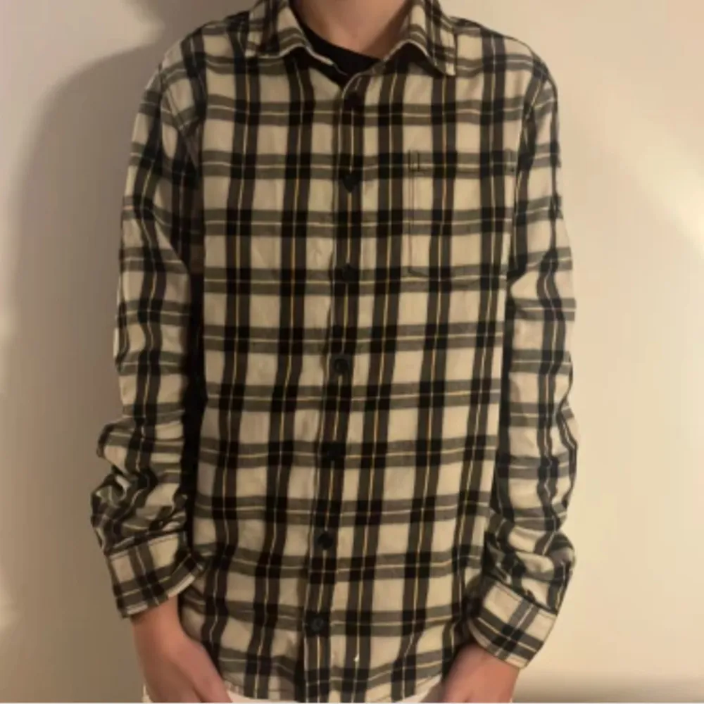 Snygg rutig skjorta från Zadig & Voltaire i svart, vit och beige. Skjortan har långa ärmar och knappar framtill. Perfekt för en stilren look med en cool text på ryggen.passar 170cm runt där xs med tags. Paidat.