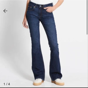 Mörkblå lågmidjade bootcut jeans - Snygga mörkblå bootcut jeans med klassisk femficksdesign och knappgylf. Perfekta för en avslappnad stil med en touch av retro. Passar bra med sneakers eller stövlar.