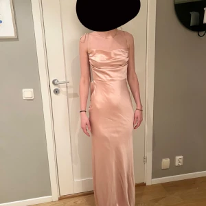 Champagnefärgad långklänning lite mer åt det rosa hållet.  - Jag säljer nu min balklänning eftersom jag inte kommer få mer användning för den. Klänningen har inga skador och har endast använt den en gång. Jag är 172 cm lång och klänningen går lite över mina fötter! Om ni har några frågor kan ni höra av er till mig! 