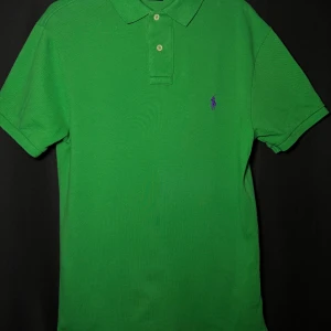 Grön pikétröja från Ralph Lauren - Läs nedan för mer info!😊 Säljer en snygg grön pikétröja från Ralph Lauren i slim fit. Tröjan har korta ärmar och en klassisk krage med knappar. Den är dekorerad med det ikoniska lila broderade logotypen på bröstet. Perfekt för en stilren look! Produktinformation:  ✅ Märke: Ralph Lauren  ✅ Storlek: M  ✅ Färg: Grön ✅ Material: Bomull ✅ Passform: Slim fit  ✅ Skick: Mycket bra skick, knappt använd  Frakt och betalning: 📦 Snabb leverans – skickar inom 1-2 dagar📦