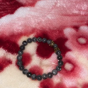 Grått armband med pärlor - Snyggt grått armband med runda pärlor och guldfärgade detaljer. Perfekt accessoar för att ge en stilren touch till din outfit.