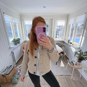 Beige kappa - Säljer en stilren beige kappa med knappar framtill. Jackan har en klassisk design med normal passform och långa ärmar. Perfekt för kyligare dagar.